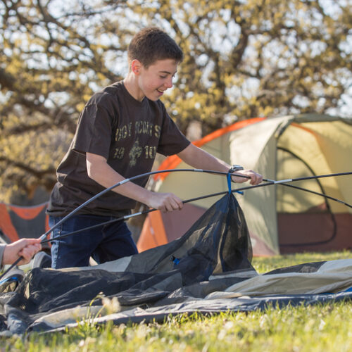 Three Scouts work together to set up a tent.
