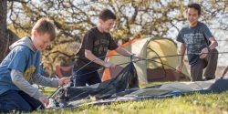 Three Scouts work together to set up a tent.